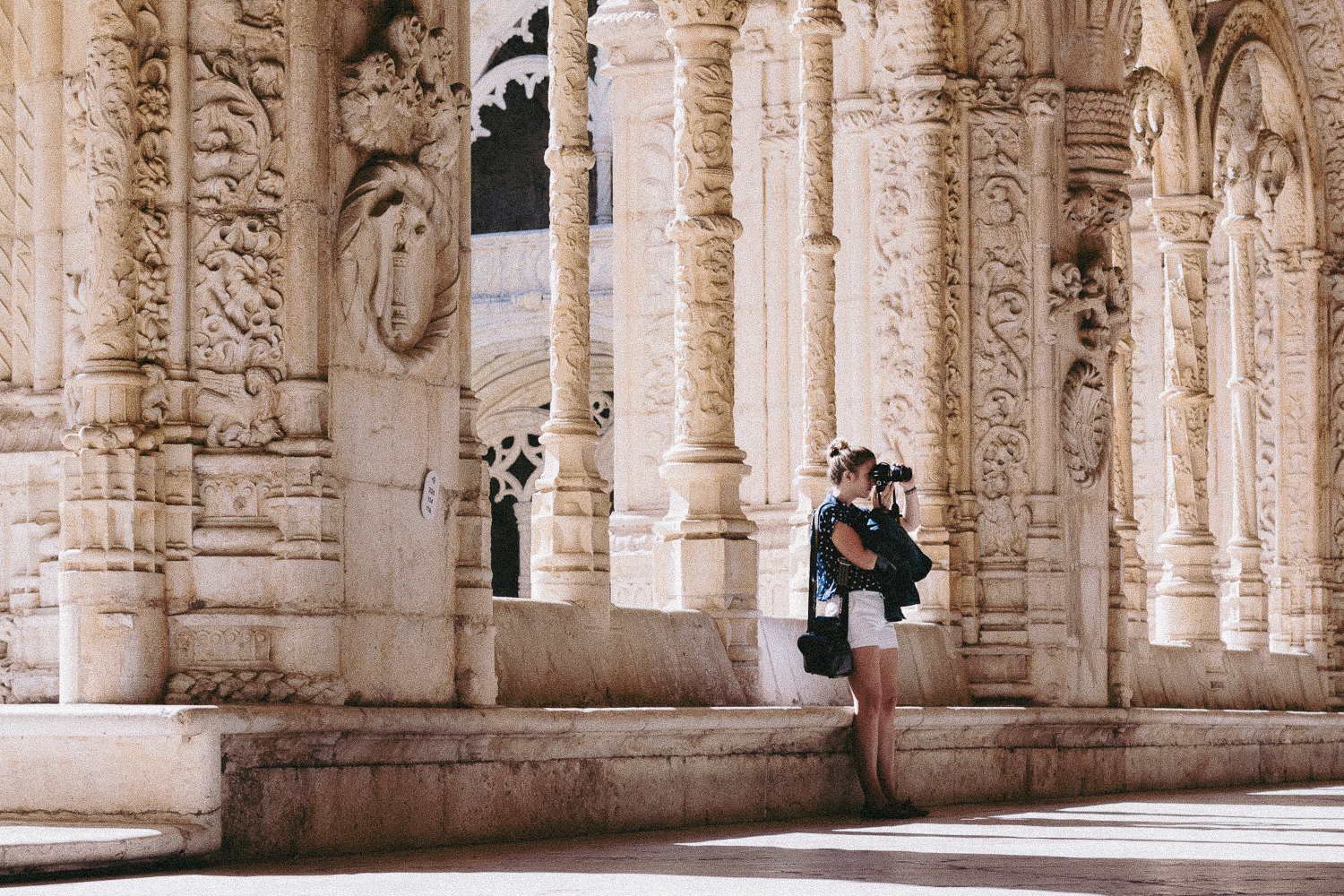 Girl taking a photo at the beautiful and intricate Jerónimos Monastery in Belem Portugal - Featured Image for Passports, Paths, & Pedals homepage